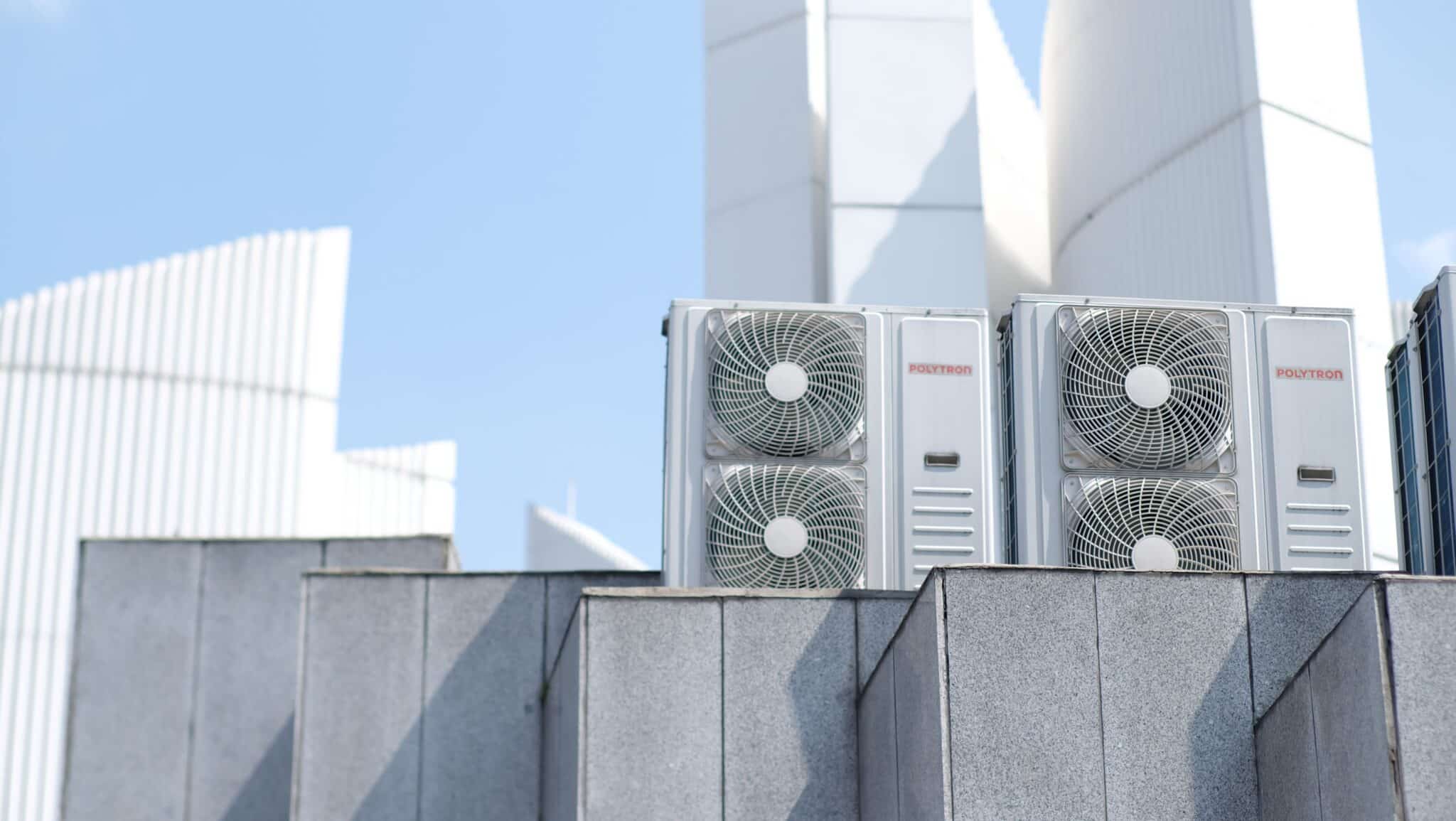 Two outdoor condenser units on a rooftop against a clear blue sky