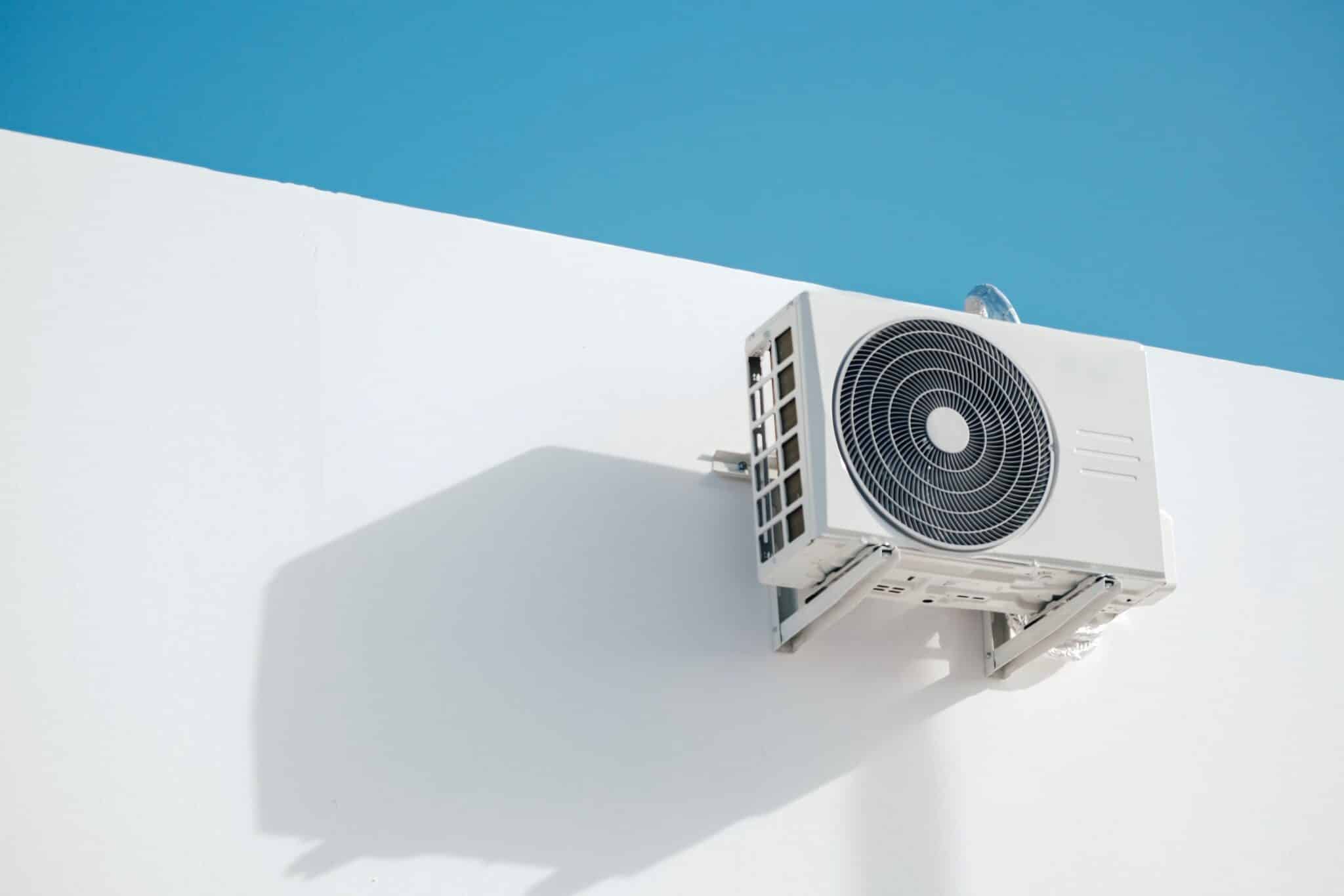 Ductless mini split outdoor unit mounted high on a white exterior wall